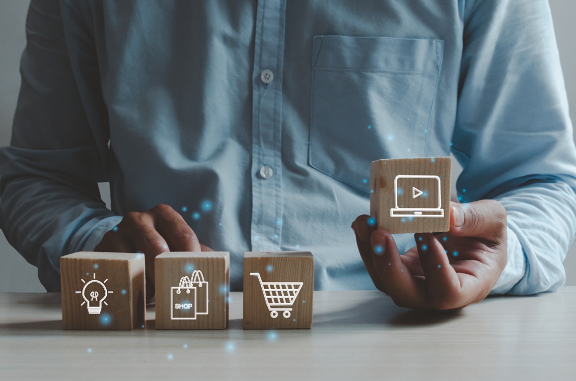 man sits in front of four small boxes with icons of a light bulb, shopping...