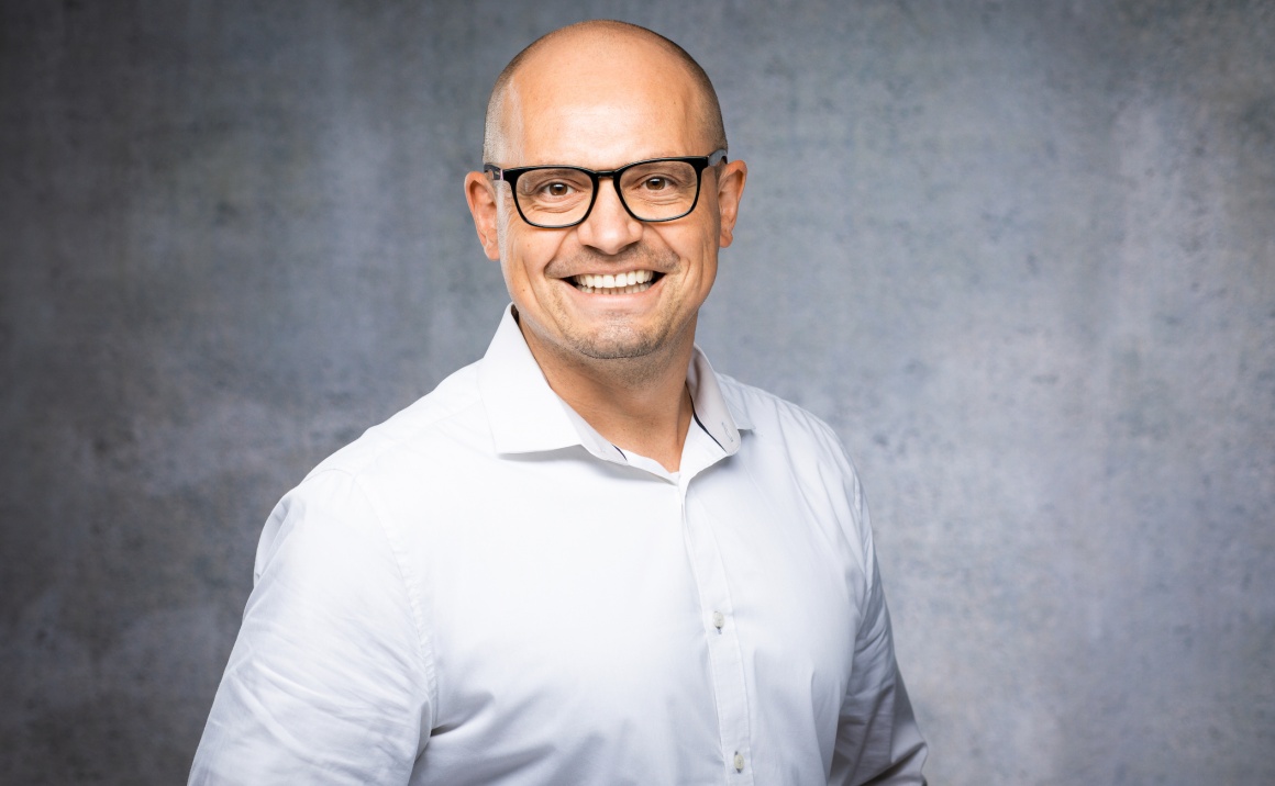 Man with glasses smiles at the camera