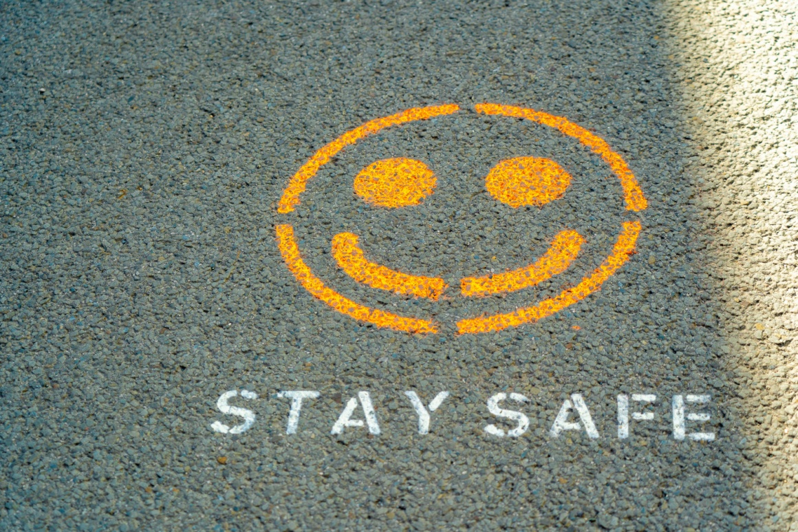 A yellow smiley on the pavement with the words stay safe under it...