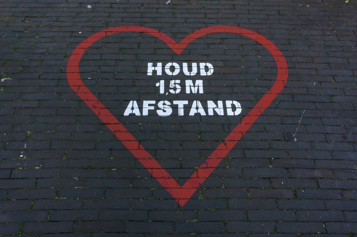 a red heart on a dark ground with a reminder to keep your distance...