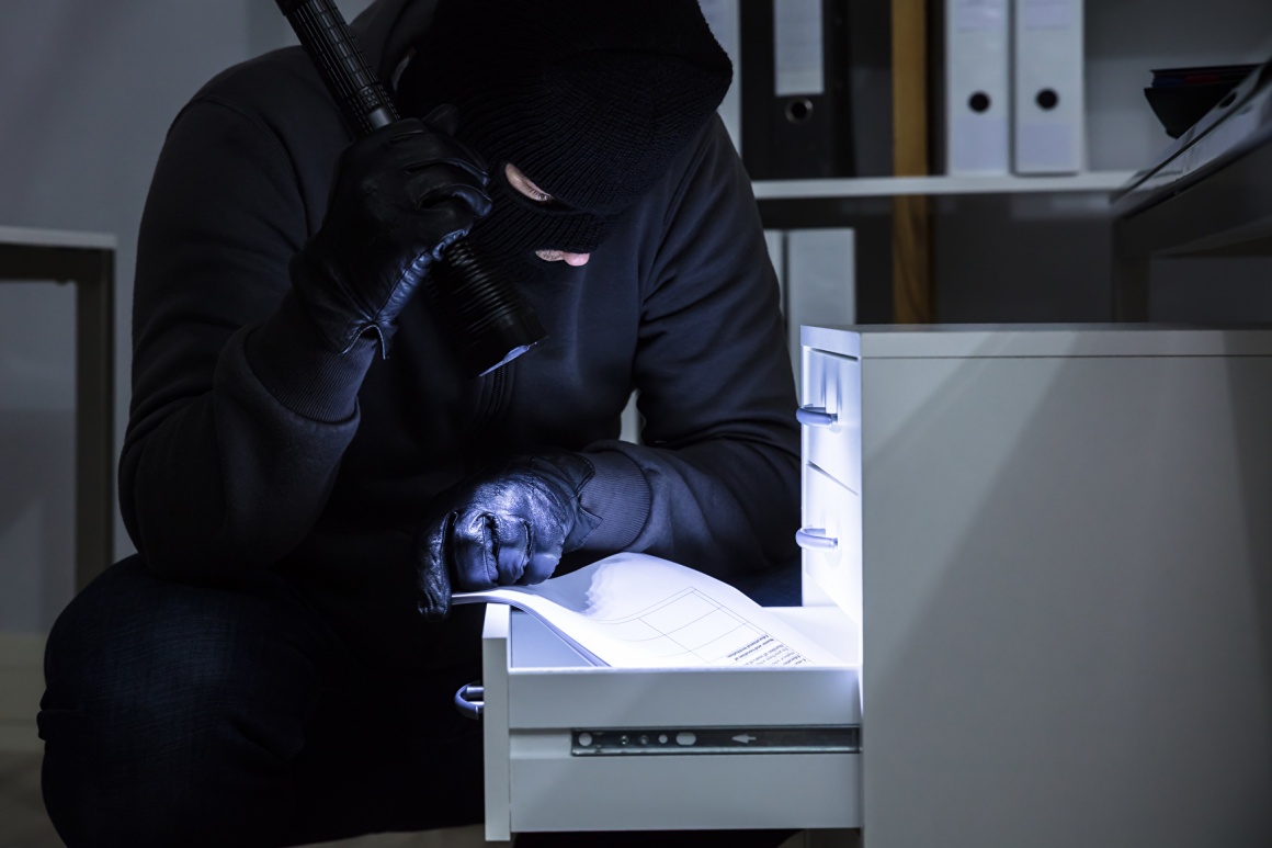 thief with flashlight looks into a drawer