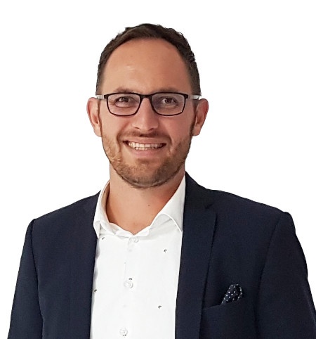 A man in a suit and glasses smiles at the camera