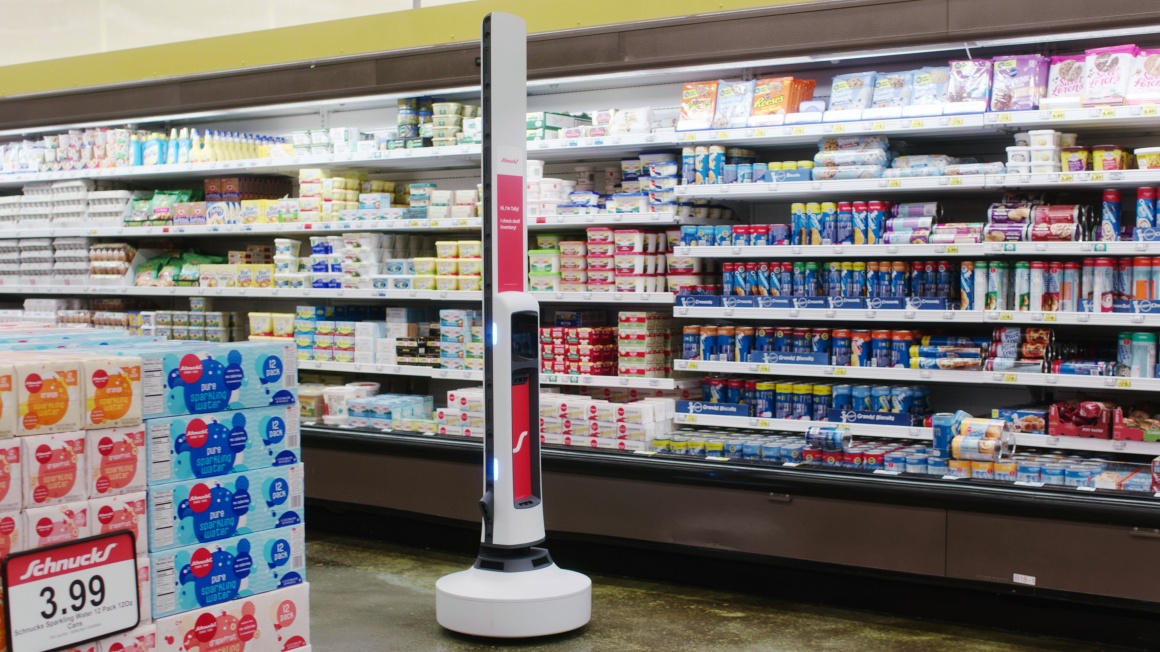 Tally the robot in front of the refrigerated shelf in a Schnuck Market...