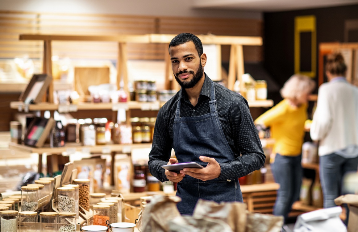 Man With Tablet In Front Of Supermarket Shelf