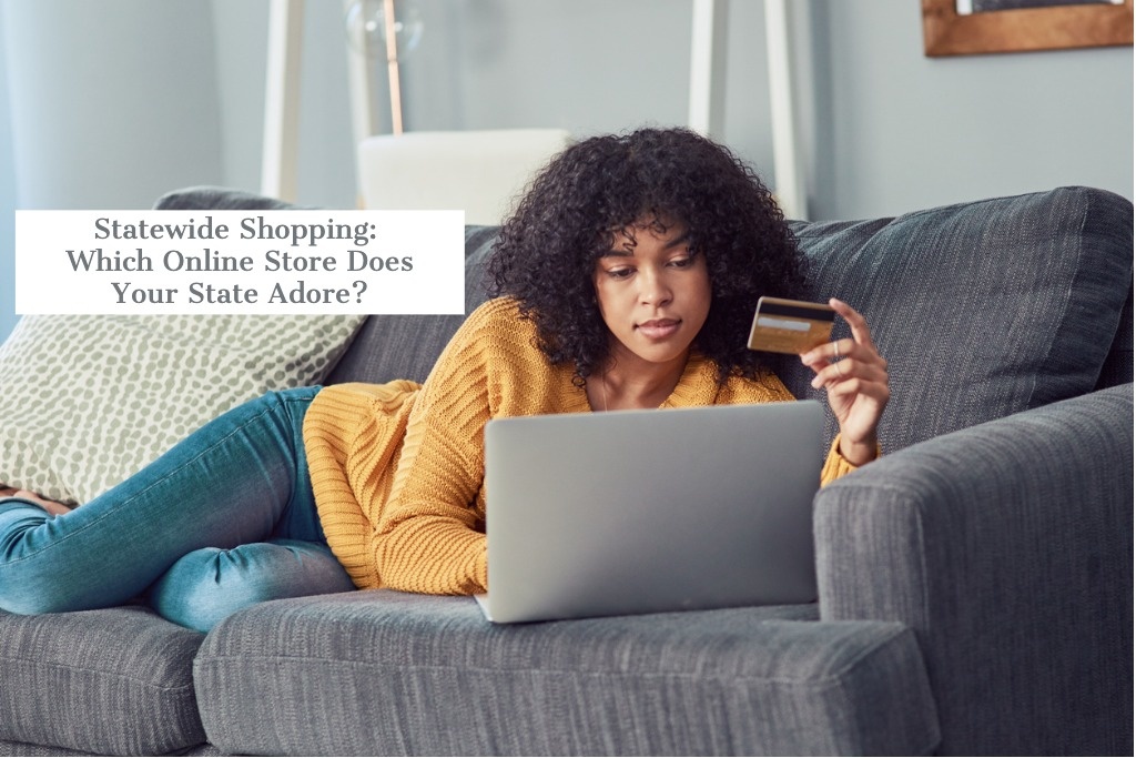 Woman holding a credit card lays on a sofa in front of a laptop...