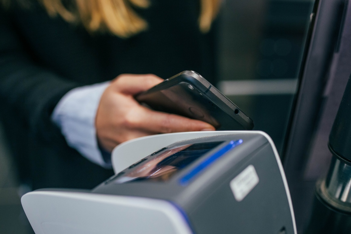 Woman holds smartphone next to a card reader