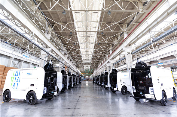 Many Alibaba delivery robots stand next to each other in a big warehouse...